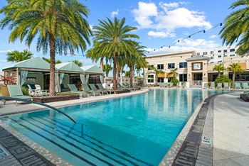 A large swimming pool surrounded by palm trees and lounge chairs.